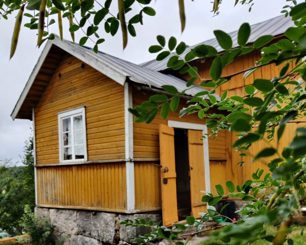 August Pyölniitun museo vihreän lehvikön takana keltainen torppa.