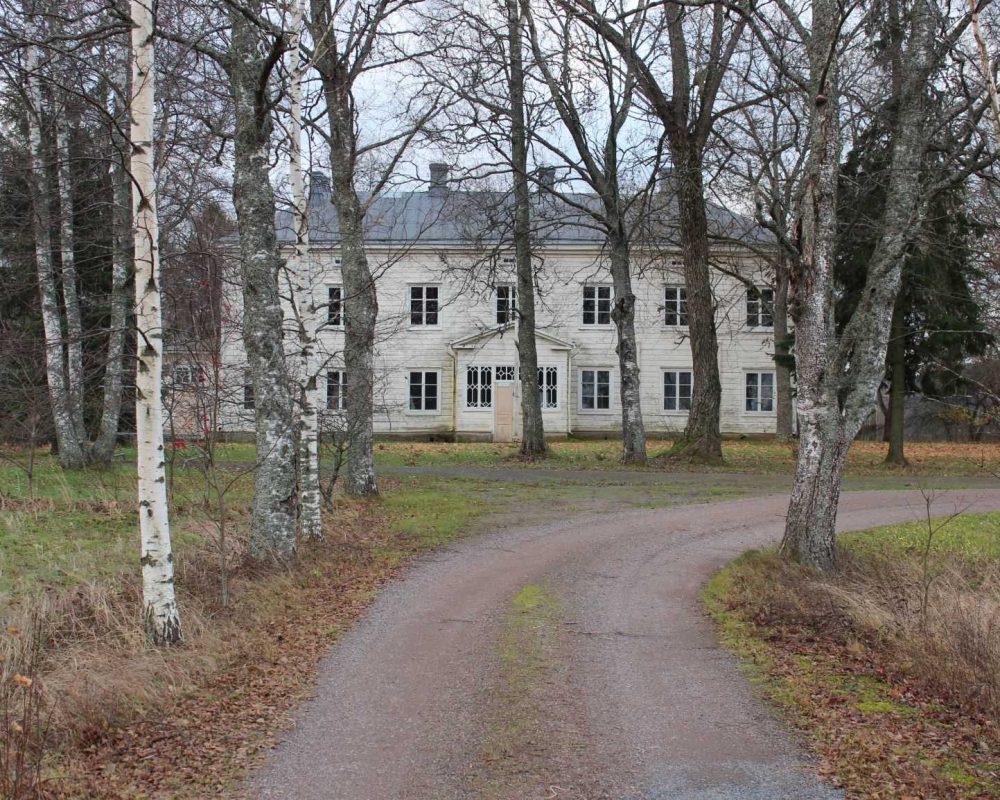 Pöytyän museopappila Pöytyän museopappila, valkoinen kaksikerroksinen puurakennus kaartuvan koivukujan päässä.
